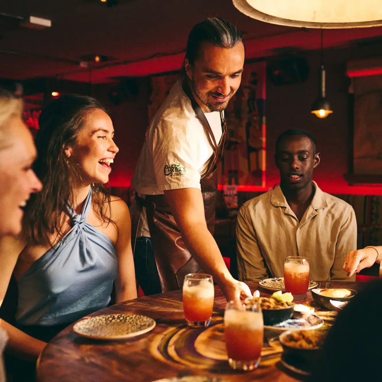 Chef serving cocktails and food to guests at Cartel's